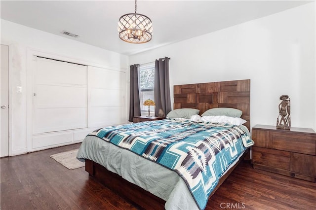 bedroom with a closet, dark hardwood / wood-style floors, and a chandelier