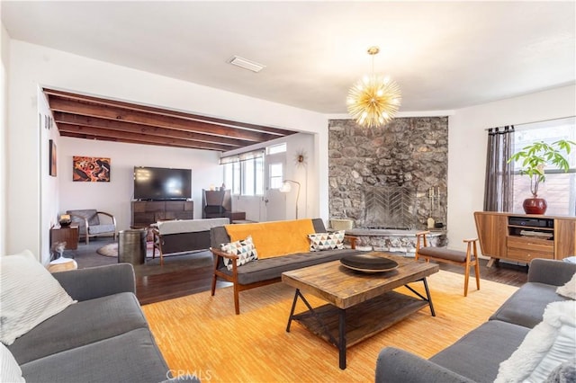 living room with beamed ceiling, a fireplace, a chandelier, and hardwood / wood-style floors