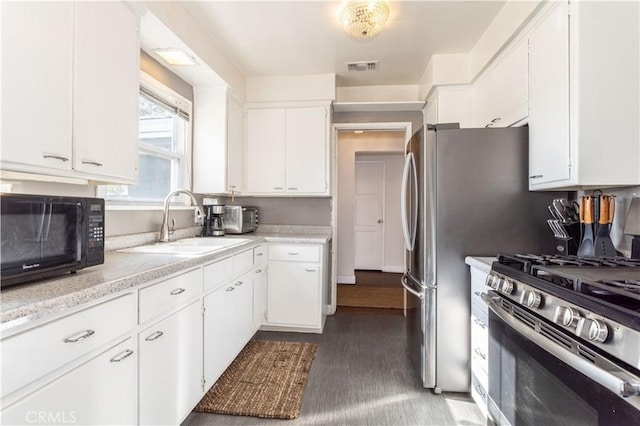 kitchen featuring white cabinetry, sink, stainless steel range with gas cooktop, and dark hardwood / wood-style flooring