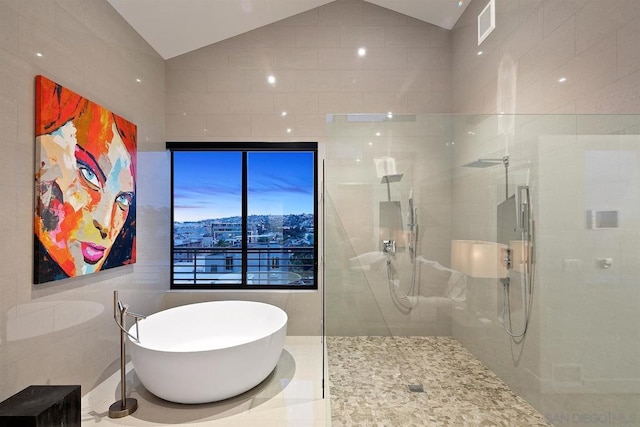 bathroom featuring independent shower and bath, lofted ceiling, and tile walls