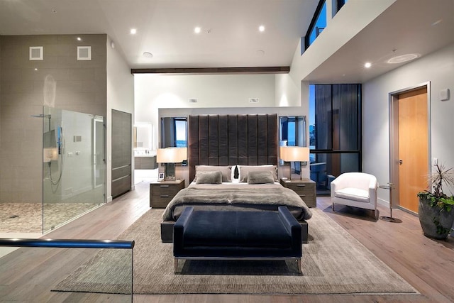 bedroom featuring a towering ceiling and light hardwood / wood-style flooring