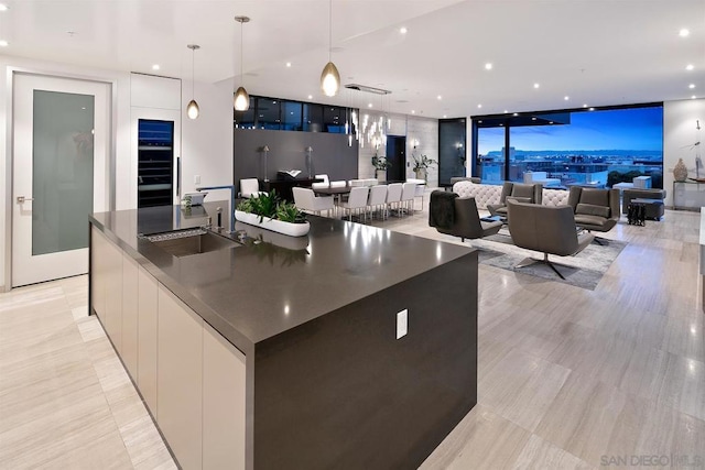 kitchen with sink, decorative light fixtures, expansive windows, and a spacious island