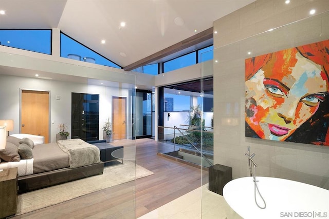 bedroom featuring high vaulted ceiling and light hardwood / wood-style flooring