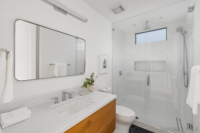 bathroom featuring a shower with door, vanity, tile patterned flooring, and toilet