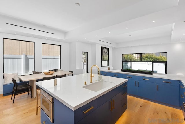 kitchen featuring a kitchen island with sink, sink, and blue cabinetry