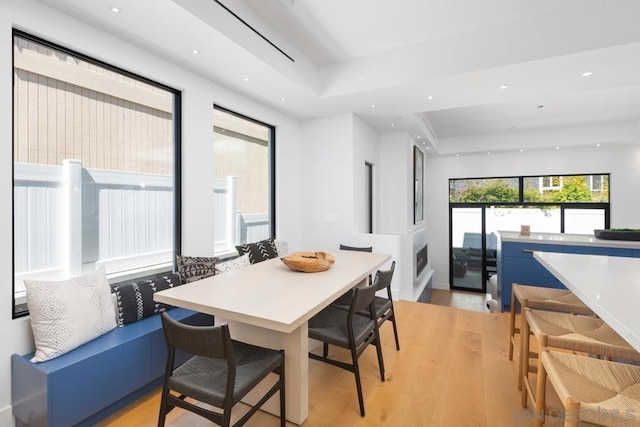 dining space with a raised ceiling and light hardwood / wood-style floors