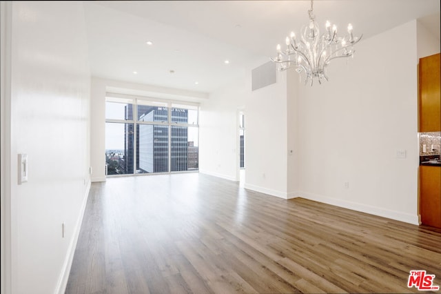 spare room with an inviting chandelier and hardwood / wood-style flooring