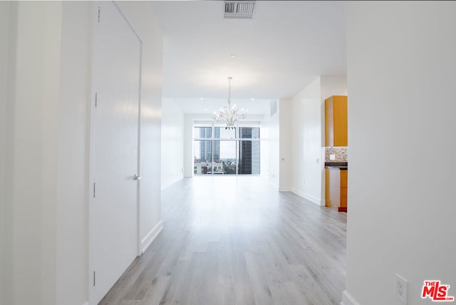 hallway featuring a chandelier and light hardwood / wood-style floors