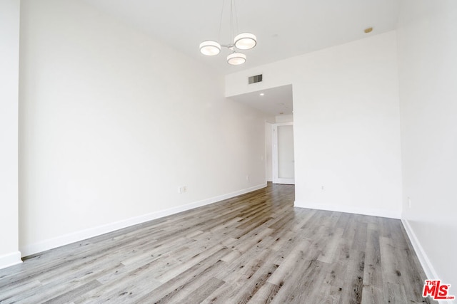 unfurnished room featuring an inviting chandelier and light hardwood / wood-style floors