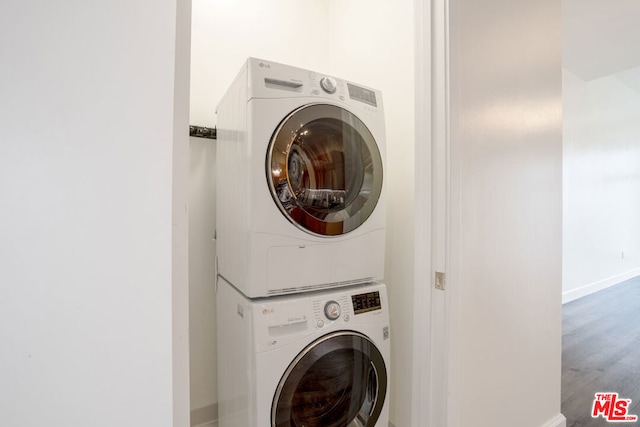 laundry area featuring stacked washing maching and dryer and hardwood / wood-style floors