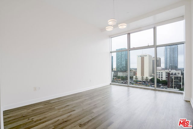 spare room featuring an inviting chandelier, floor to ceiling windows, and hardwood / wood-style floors