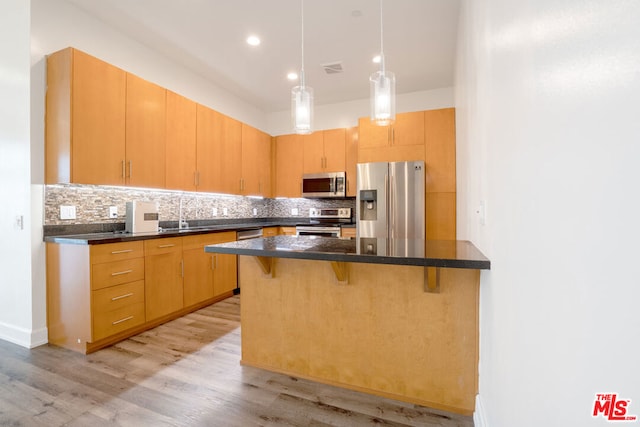 kitchen with sink, a breakfast bar area, stainless steel appliances, light hardwood / wood-style floors, and backsplash