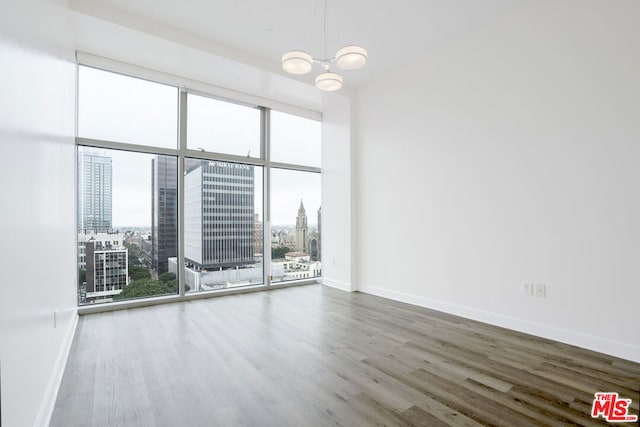 empty room with a healthy amount of sunlight, hardwood / wood-style floors, and an inviting chandelier