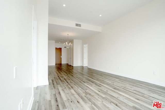 empty room featuring a chandelier and light wood-type flooring