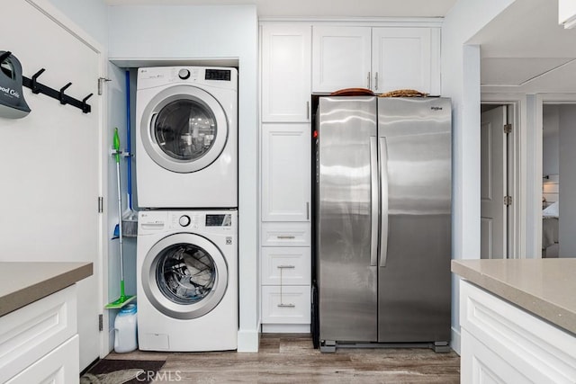 washroom with stacked washer and clothes dryer and hardwood / wood-style floors