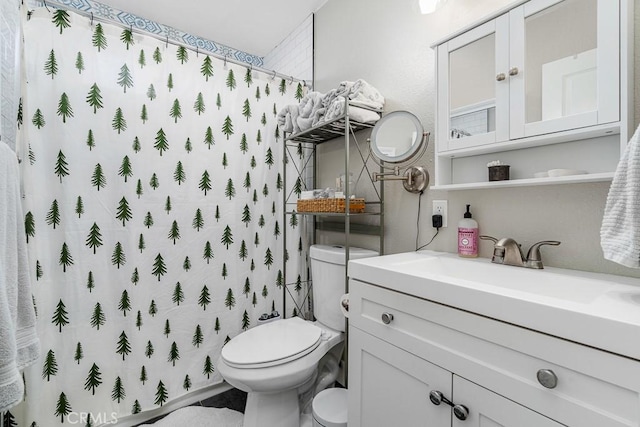 bathroom featuring toilet, vanity, and walk in shower