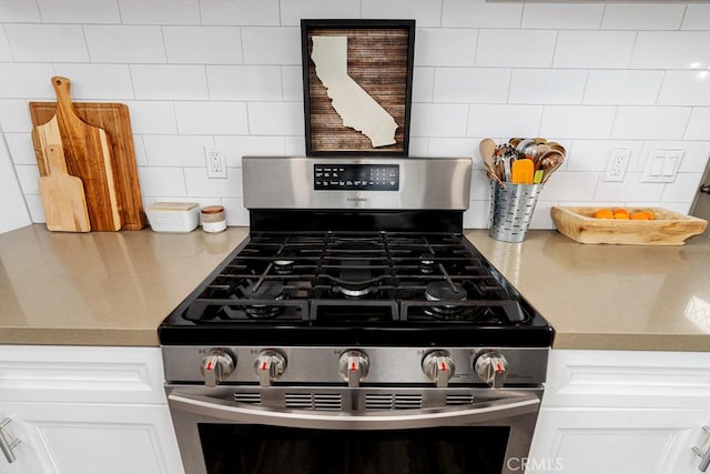 room details with white cabinetry, stainless steel range with gas cooktop, and backsplash