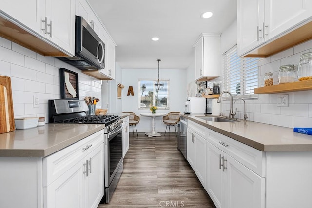 kitchen with dark wood-type flooring, sink, decorative light fixtures, stainless steel appliances, and white cabinets