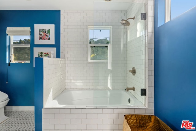 bathroom featuring tiled shower / bath, tile patterned floors, and toilet