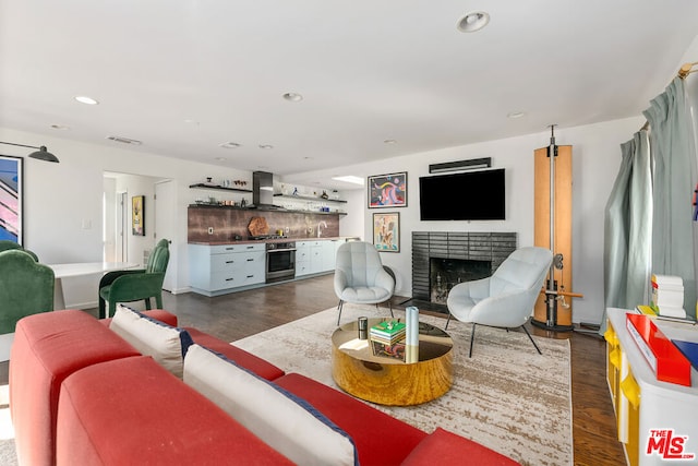 living room with a brick fireplace, dark hardwood / wood-style floors, and bar area