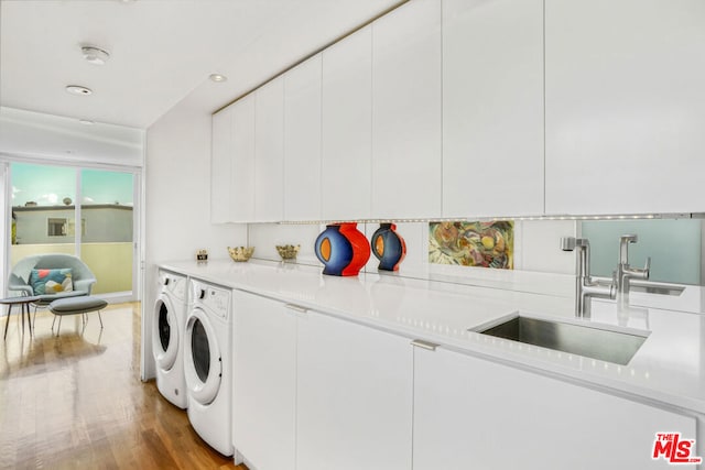 laundry room with cabinets, washing machine and clothes dryer, dark wood-type flooring, and sink