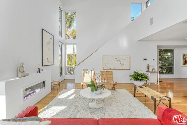 living room with a towering ceiling and light wood-type flooring