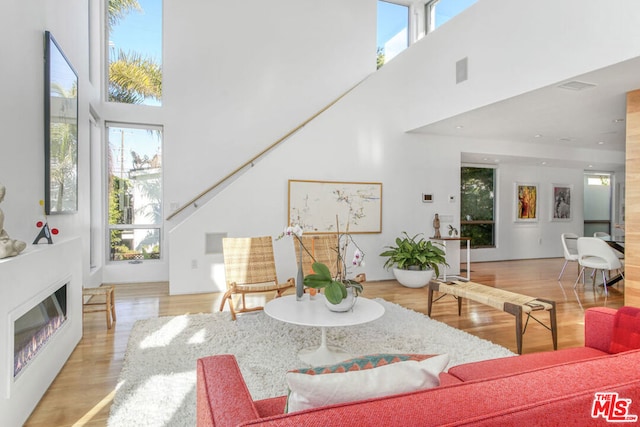 living room with a towering ceiling and light hardwood / wood-style floors