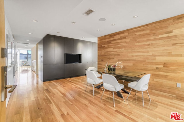 dining area with light hardwood / wood-style floors and wood walls