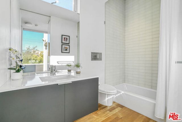 full bathroom with wood-type flooring, toilet, shower / bath combination with curtain, and vanity