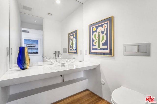 bathroom with hardwood / wood-style flooring, toilet, and sink