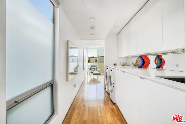 laundry room with plenty of natural light, washer and clothes dryer, and light hardwood / wood-style flooring