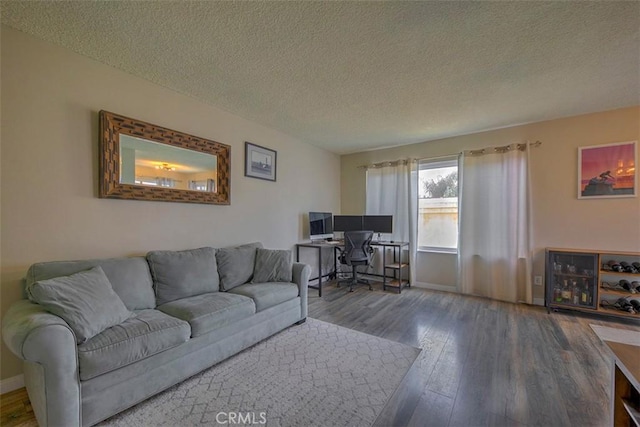 living area with a textured ceiling, wood finished floors, and baseboards