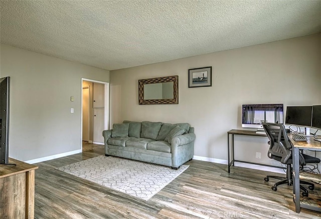 home office featuring a textured ceiling, wood finished floors, and baseboards