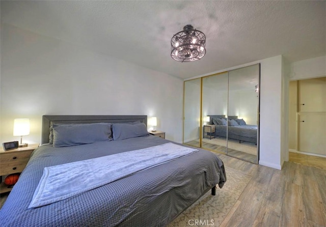 bedroom featuring an inviting chandelier, hardwood / wood-style floors, and a closet