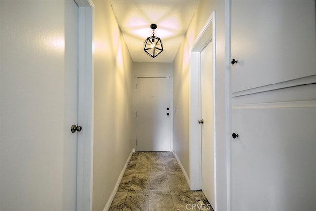 hallway with stone finish floor and baseboards