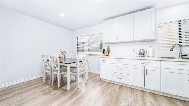 kitchen featuring white cabinetry, sink, and light hardwood / wood-style flooring