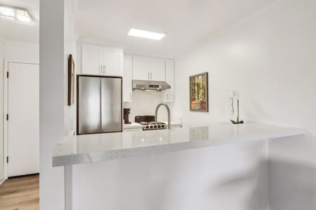 kitchen featuring white cabinetry, light stone counters, stainless steel fridge, kitchen peninsula, and light hardwood / wood-style floors