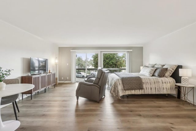 bedroom featuring ornamental molding, wood-type flooring, and access to outside