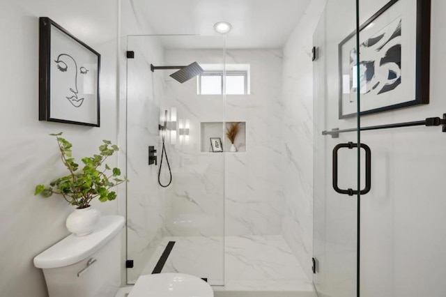 bathroom featuring a shower with shower door and toilet