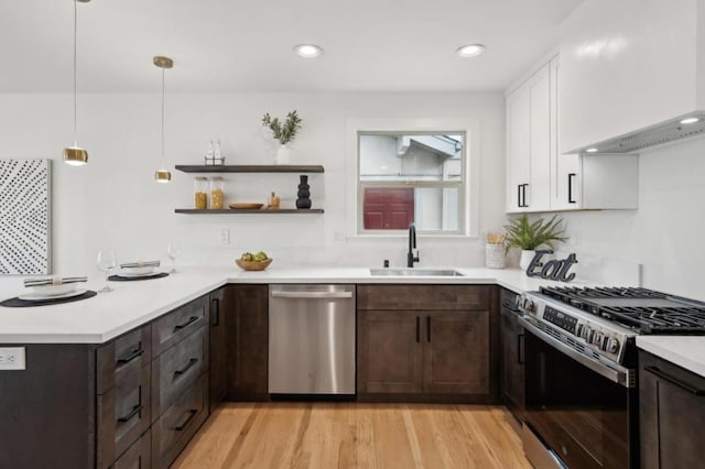 kitchen with pendant lighting, sink, white cabinetry, dark brown cabinets, and stainless steel appliances