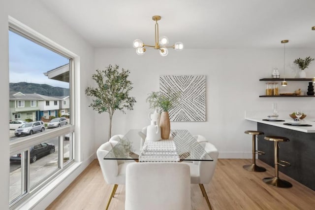 dining space with light hardwood / wood-style floors and a notable chandelier