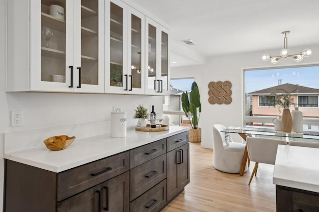 kitchen with pendant lighting, white cabinets, dark brown cabinetry, and light hardwood / wood-style flooring