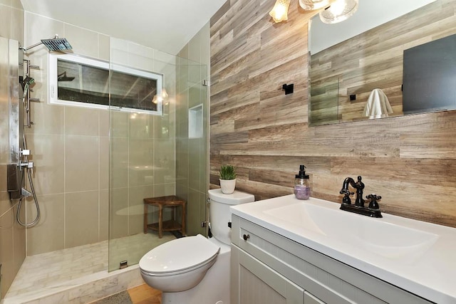 bathroom featuring a tile shower, vanity, toilet, and wood walls