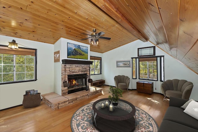 living room with wood ceiling, hardwood / wood-style floors, vaulted ceiling with beams, plenty of natural light, and a stone fireplace