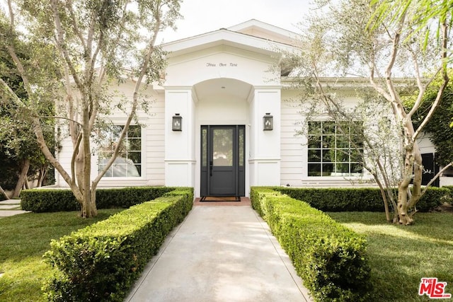 entrance to property featuring a lawn