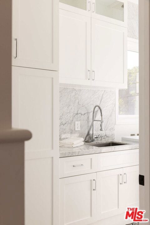 bar with sink, decorative backsplash, and white cabinets