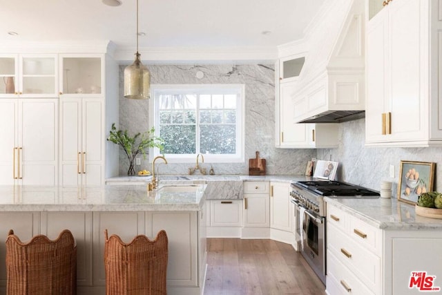 kitchen with white cabinetry, decorative light fixtures, high end stainless steel range, and light stone counters