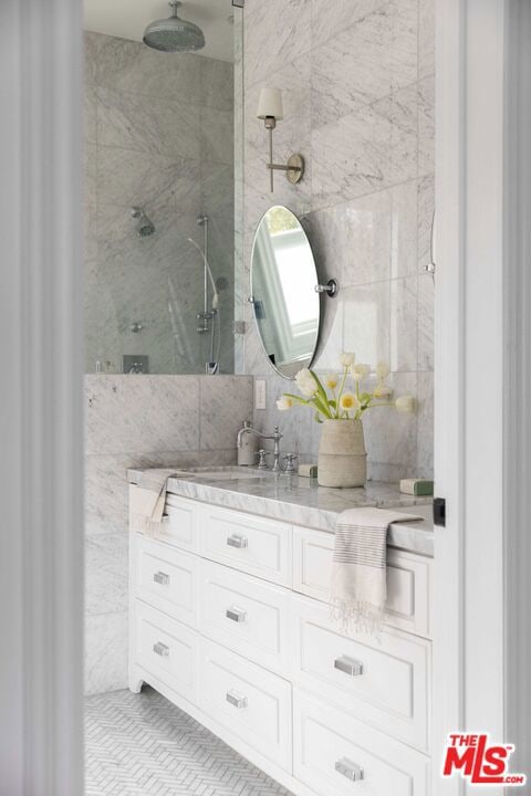 bathroom featuring decorative backsplash, vanity, tile walls, and a tile shower