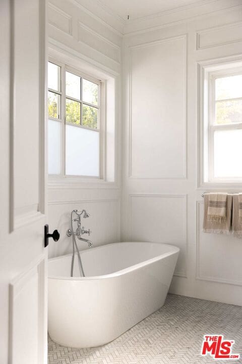 bathroom featuring ornamental molding, a tub, and a wealth of natural light