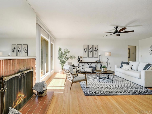 living room featuring ceiling fan, a fireplace, and hardwood / wood-style floors